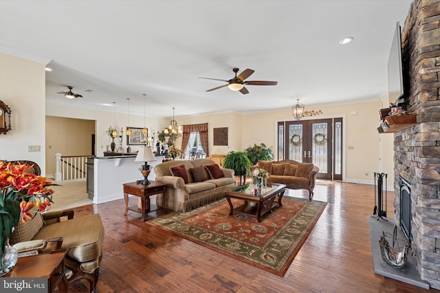 living room featuring ceiling fan with notable chandelier, plenty of natural light, baseboards, and wood finished floors