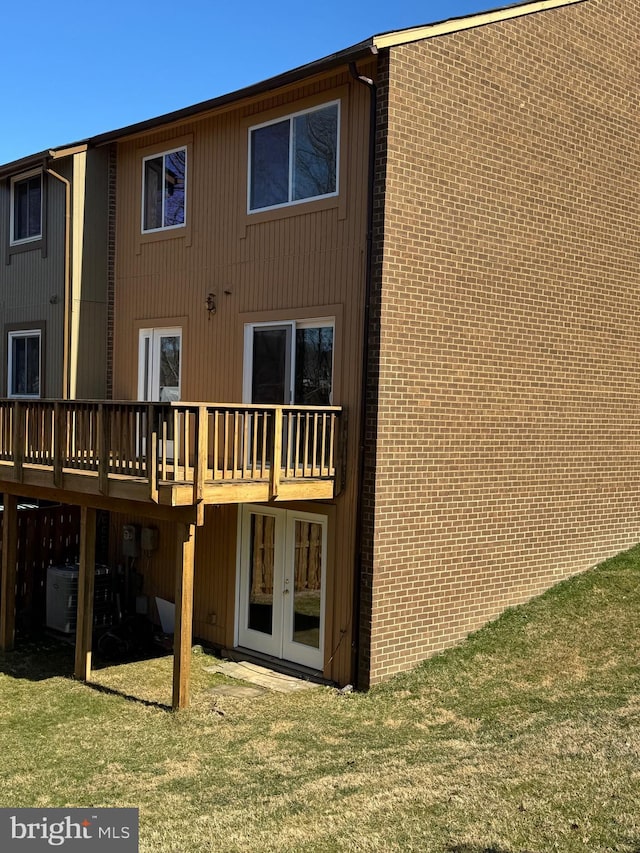 rear view of house featuring a deck, a lawn, and french doors