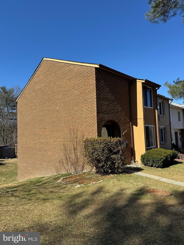 view of home's exterior featuring brick siding and a lawn