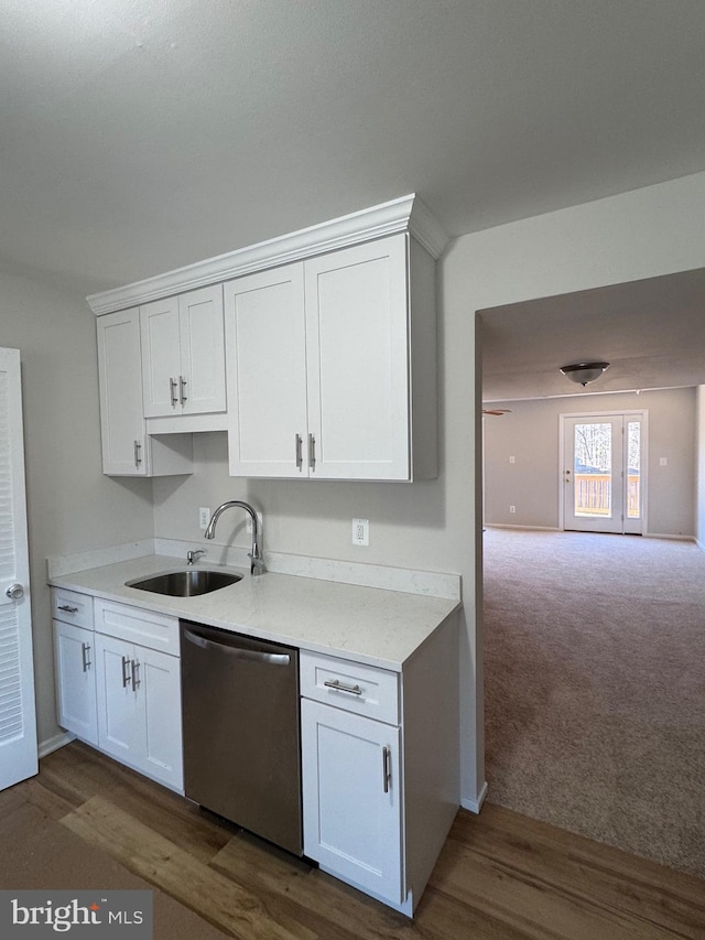 kitchen with light countertops, stainless steel dishwasher, a sink, and white cabinetry