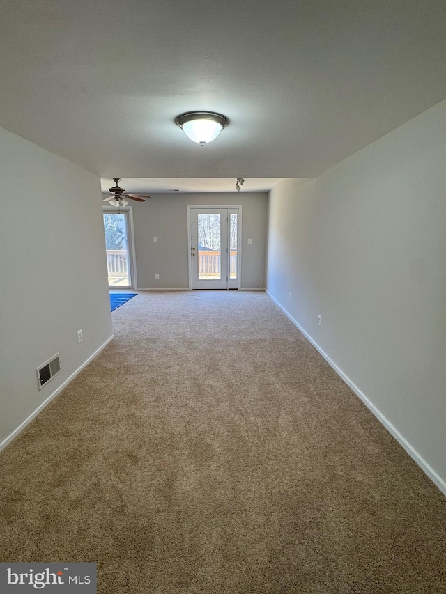 carpeted spare room with visible vents, ceiling fan, and baseboards