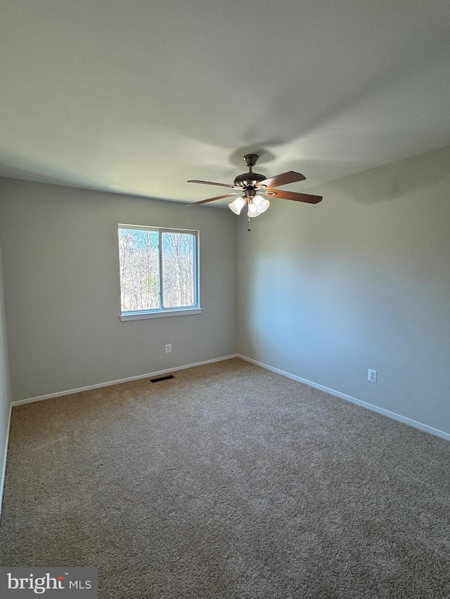 carpeted empty room featuring baseboards, visible vents, and a ceiling fan