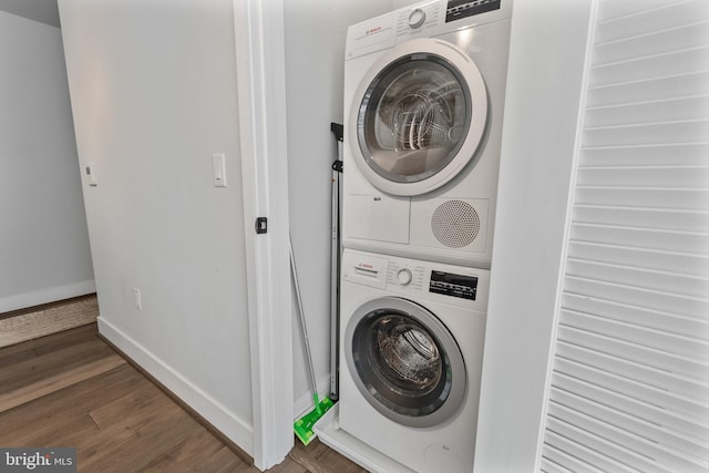 laundry area with baseboards, laundry area, wood finished floors, and stacked washer / drying machine