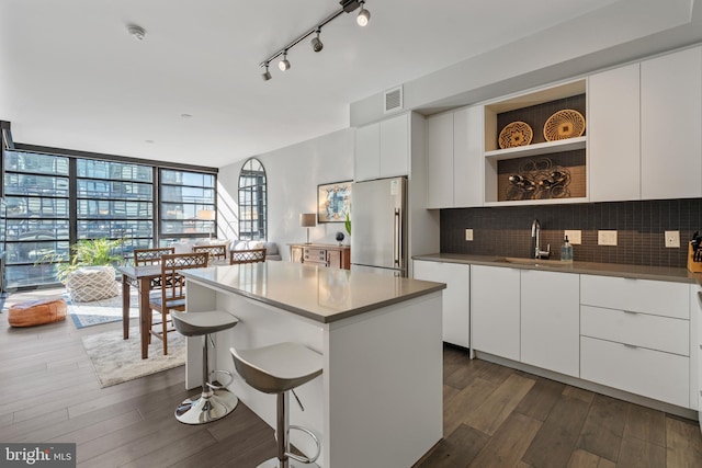 kitchen with high quality fridge, decorative backsplash, open shelves, and a sink