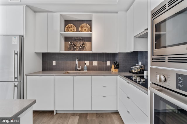 kitchen with stainless steel appliances, modern cabinets, a sink, and white cabinets