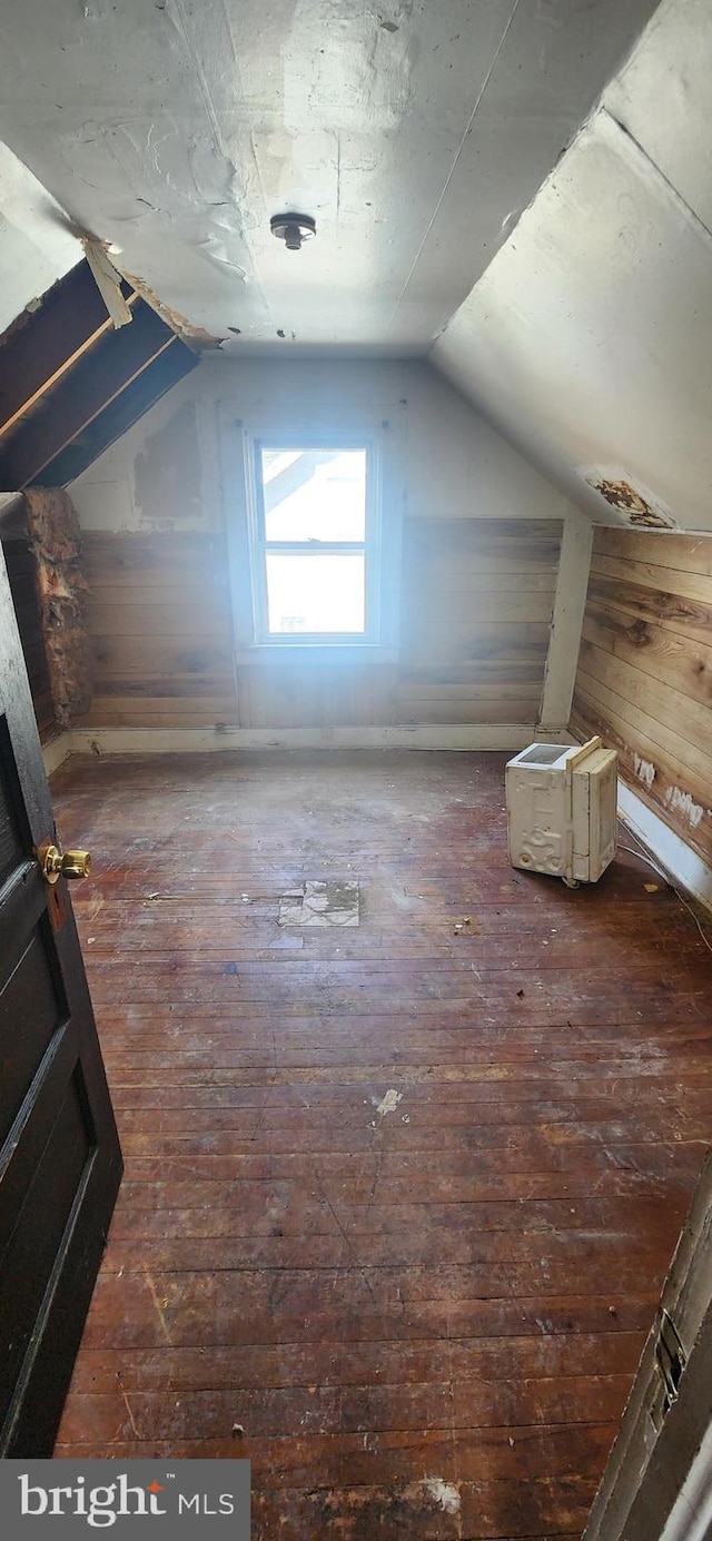 bonus room featuring lofted ceiling, wooden walls, and hardwood / wood-style floors