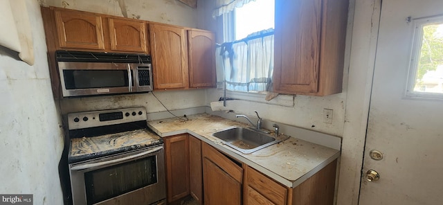 kitchen featuring brown cabinets, appliances with stainless steel finishes, light countertops, and a sink