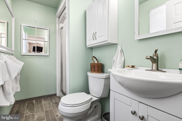 full bath with wood finish floors, a shower with shower door, vanity, and toilet