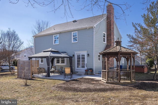 back of property with a patio, a chimney, a hot tub, a gazebo, and entry steps