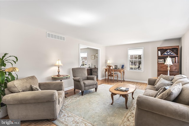 living area with wood finished floors, visible vents, and baseboards