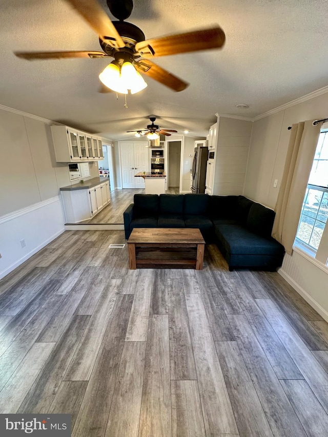 living room with a textured ceiling, ornamental molding, and wood finished floors