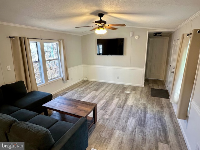 living room featuring crown molding, lofted ceiling, a ceiling fan, a textured ceiling, and wood finished floors