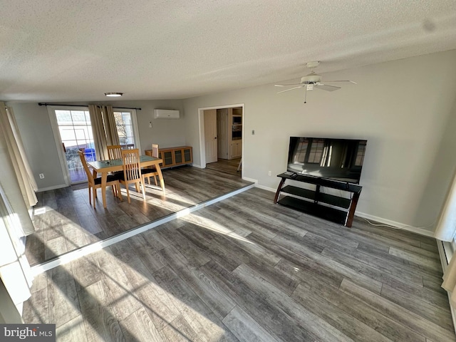 dining space featuring a textured ceiling, baseboards, wood finished floors, and a wall mounted air conditioner