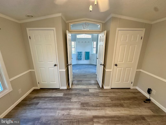 interior space with ornamental molding, vaulted ceiling, baseboards, and wood finished floors