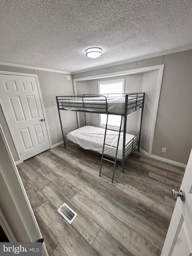 unfurnished bedroom featuring crown molding, visible vents, and wood finished floors