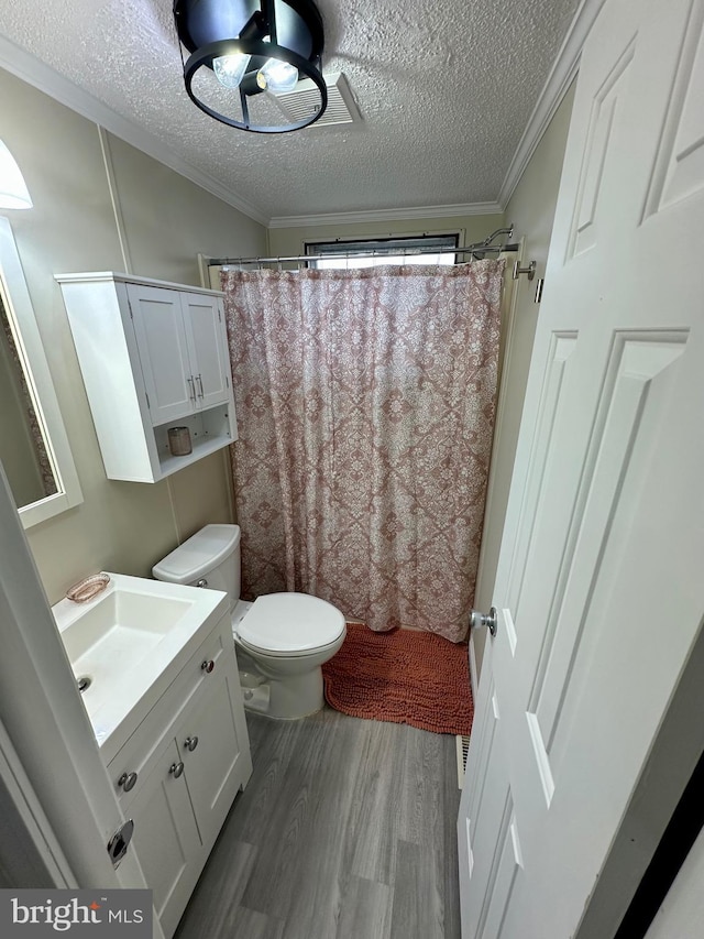 bathroom featuring toilet, ornamental molding, wood finished floors, a textured ceiling, and vanity