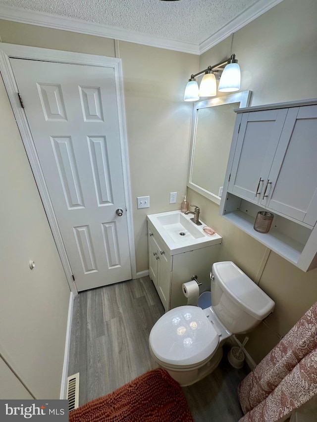 half bathroom with toilet, a textured ceiling, visible vents, and wood finished floors