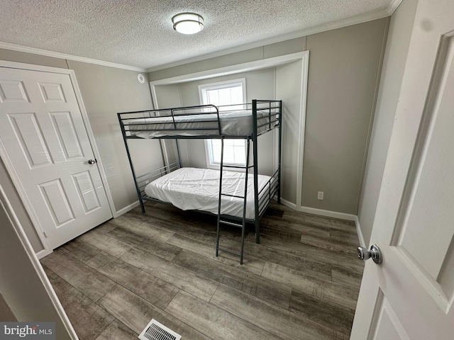 bedroom with baseboards, wood finished floors, visible vents, and crown molding