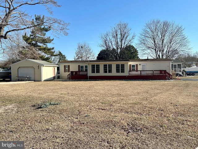 manufactured / mobile home featuring a garage, a wooden deck, a front lawn, and an outbuilding