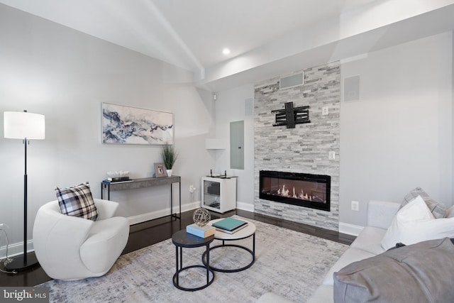 living area with vaulted ceiling, a fireplace, baseboards, and wood finished floors