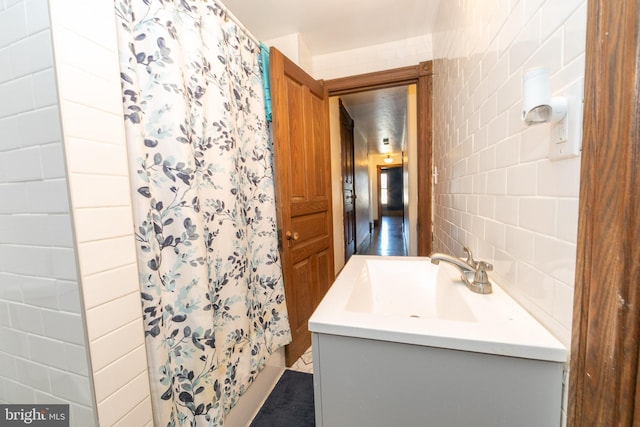 full bath featuring tasteful backsplash, a shower with curtain, tile walls, and vanity