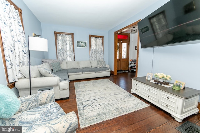 living area featuring dark wood-style flooring and a healthy amount of sunlight