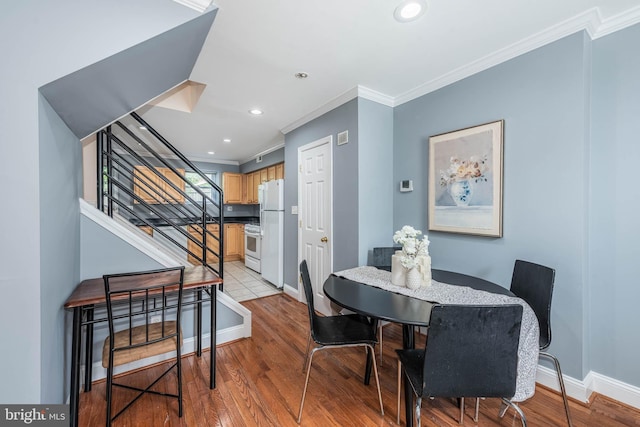 dining room featuring light wood finished floors, baseboards, stairs, and ornamental molding