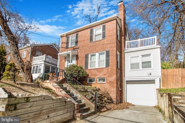 view of front of property featuring a garage, driveway, a chimney, stairs, and brick siding