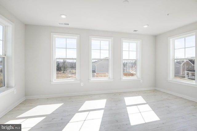 empty room featuring light wood-style floors, baseboards, and visible vents