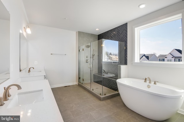 full bathroom with double vanity, a freestanding tub, a sink, and a shower stall