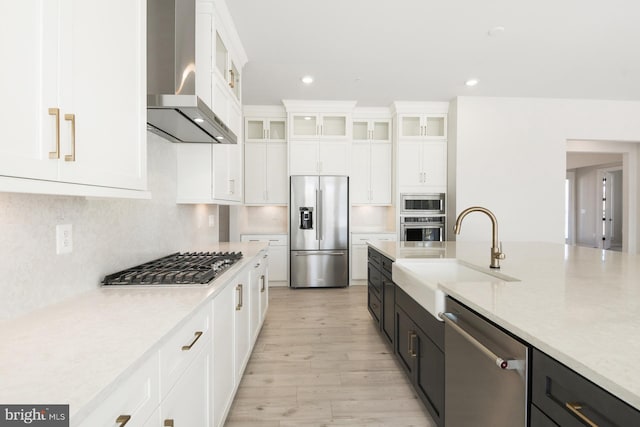 kitchen featuring a sink, light countertops, appliances with stainless steel finishes, and wall chimney range hood