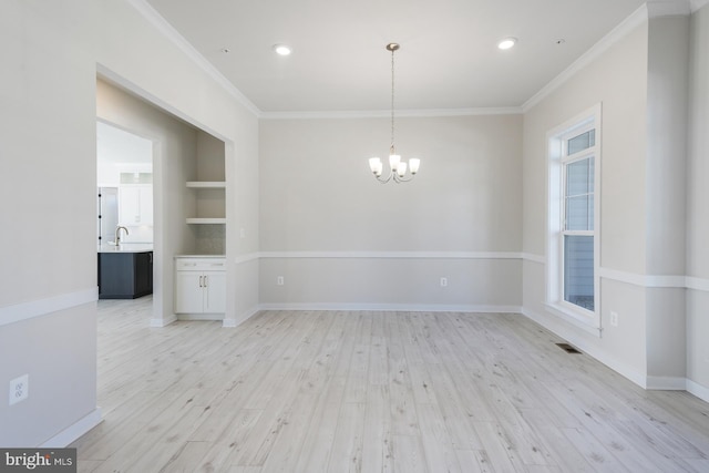 unfurnished room featuring light wood-style flooring, a notable chandelier, visible vents, baseboards, and crown molding