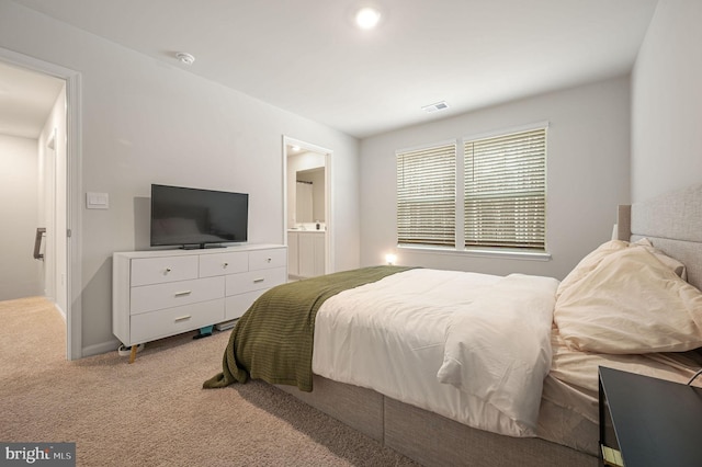 bedroom featuring light colored carpet, visible vents, and ensuite bath