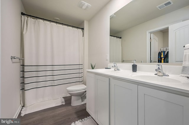 full bath featuring double vanity, visible vents, a sink, and wood finished floors