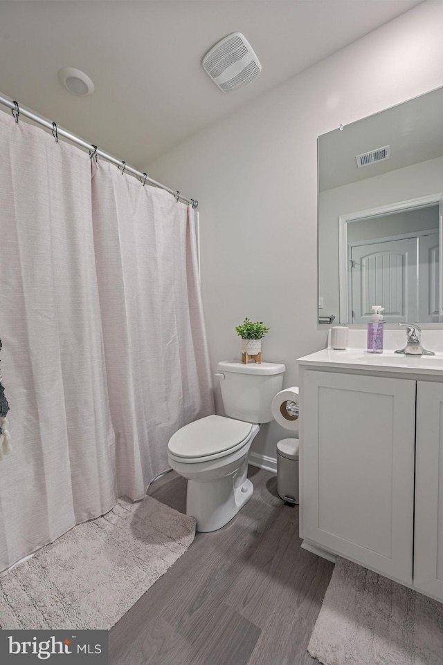 full bath featuring toilet, visible vents, wood finished floors, and vanity