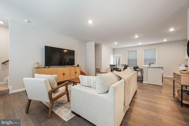 living room with stairs, light wood-type flooring, baseboards, and recessed lighting