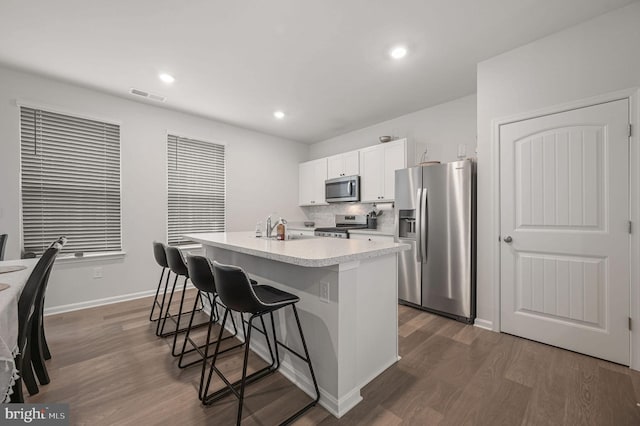 kitchen with visible vents, appliances with stainless steel finishes, a breakfast bar, dark wood-style flooring, and a sink