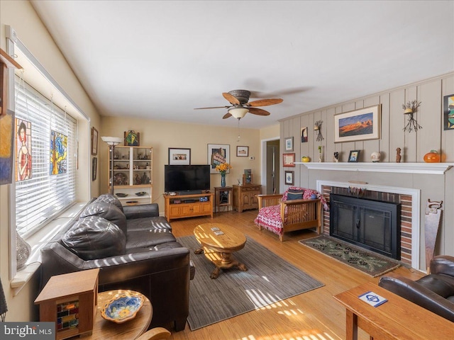 living area with ceiling fan, a fireplace, and wood finished floors