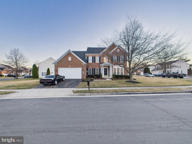 view of front of house with driveway, a garage, a front yard, and brick siding