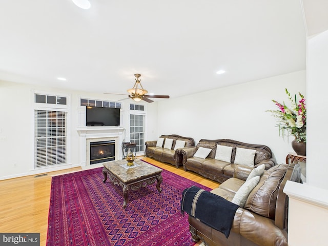 living room featuring a warm lit fireplace, ceiling fan, recessed lighting, visible vents, and light wood finished floors