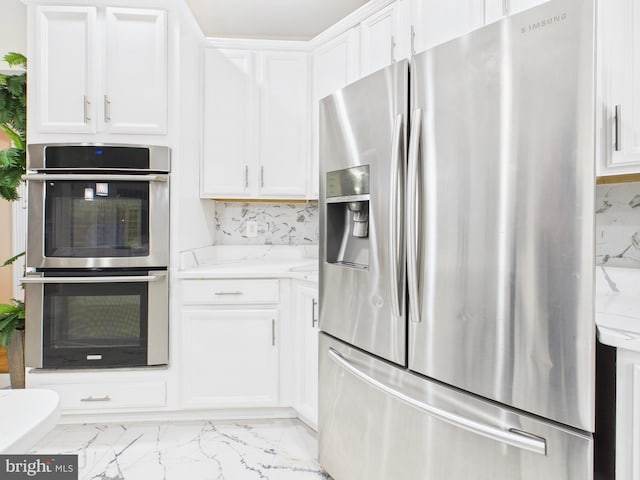 kitchen with stainless steel appliances, marble finish floor, white cabinetry, and decorative backsplash