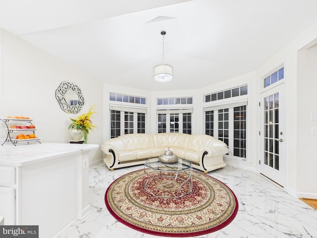 living room with lofted ceiling, marble finish floor, and baseboards