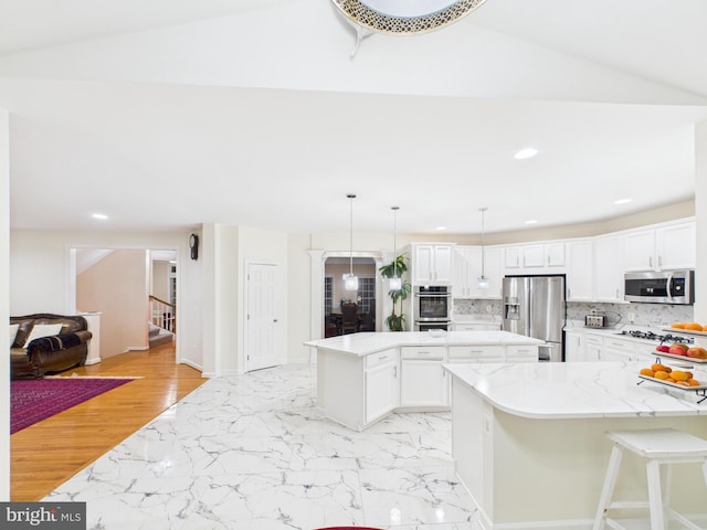 kitchen with stainless steel appliances, a kitchen island, white cabinets, marble finish floor, and decorative backsplash