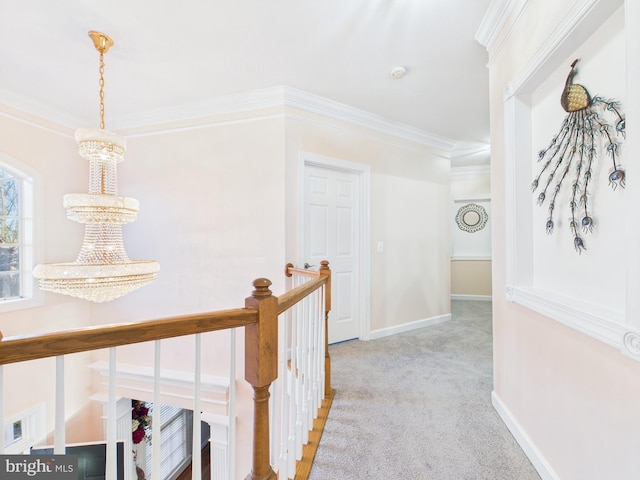 hall featuring baseboards, ornamental molding, carpet flooring, and an upstairs landing