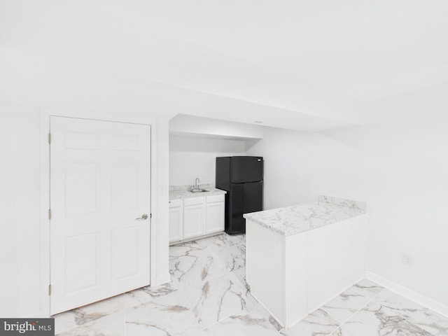 kitchen featuring baseboards, freestanding refrigerator, a peninsula, marble finish floor, and a sink