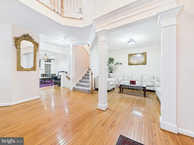 entryway featuring decorative columns, stairway, light wood-style flooring, and crown molding