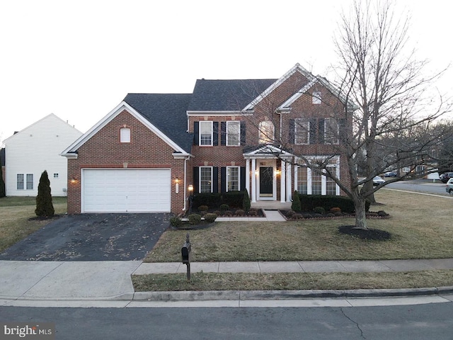 view of front of property with driveway, brick siding, a front lawn, and an attached garage