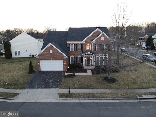 view of front of house featuring a garage, a front yard, brick siding, and driveway