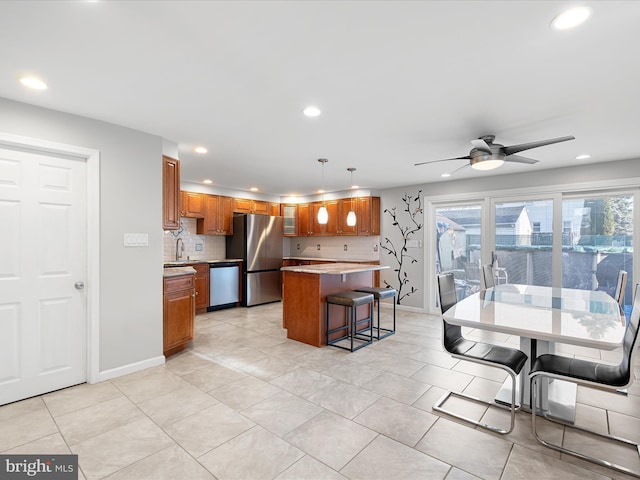 kitchen with brown cabinetry, appliances with stainless steel finishes, light countertops, a kitchen bar, and recessed lighting