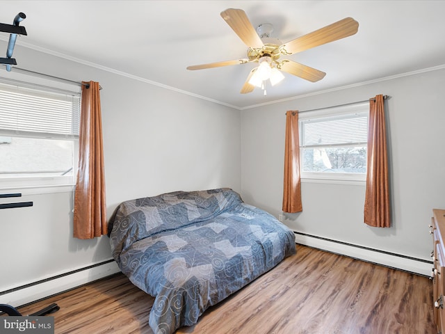 bedroom with a baseboard heating unit, wood finished floors, and ornamental molding